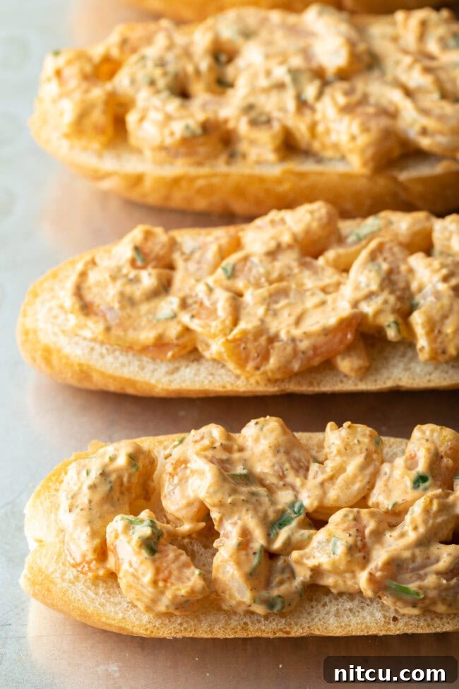 Four pieces of baguette with the savory shrimp and mayonnaise mixture spread evenly across their surfaces, ready for cheese.