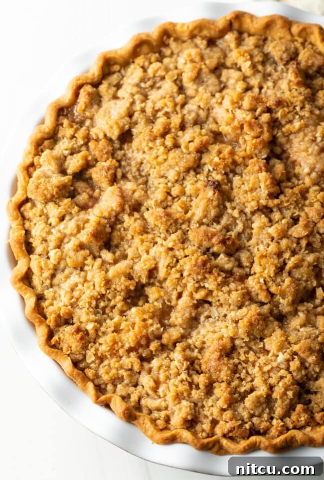 Top view of a beautifully baked peach crumble pie, showing the golden-brown, crispy oat topping.