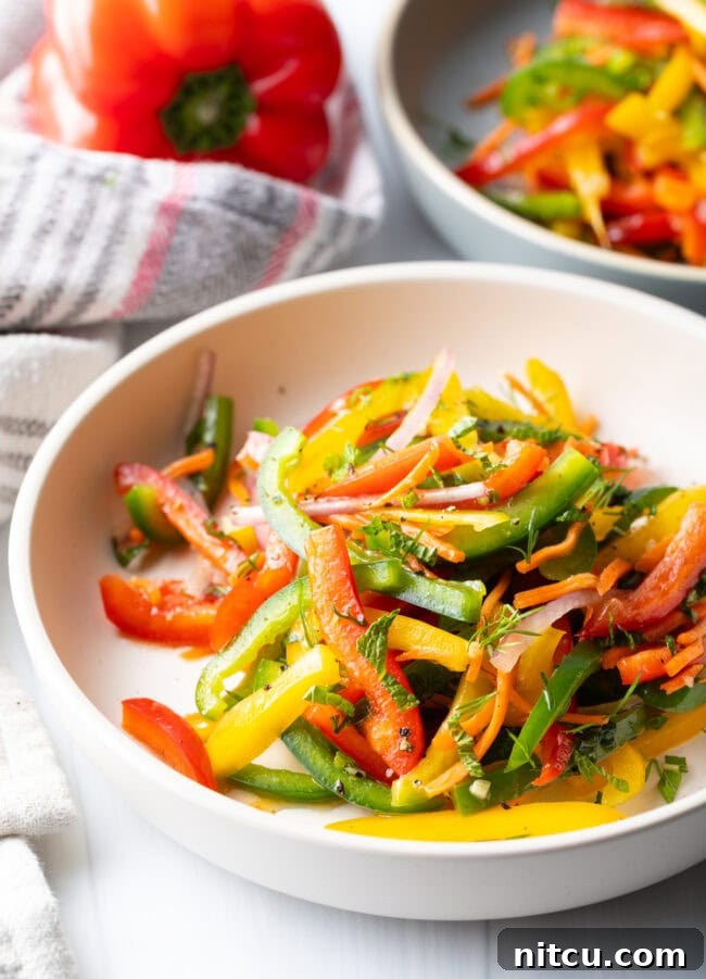 A side view of the colorful bell pepper salad, showing a fork taking a portion, emphasizing its fresh ingredients.