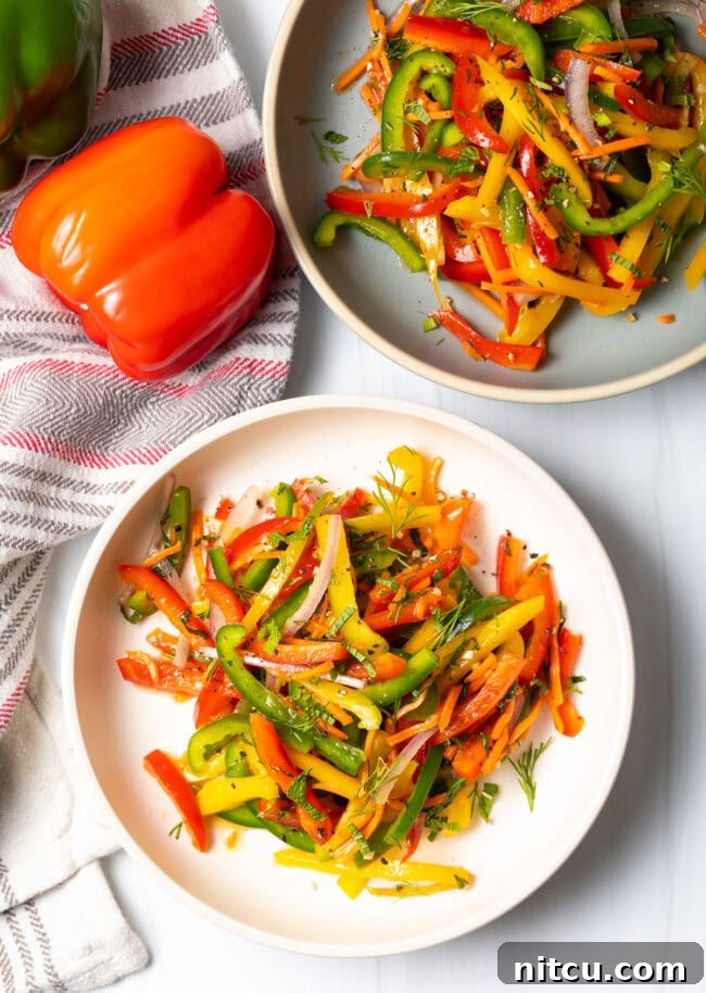 A top-down view of a vibrant summer bell pepper salad, generously served in a shallow white bowl, showcasing a mix of colorful peppers.