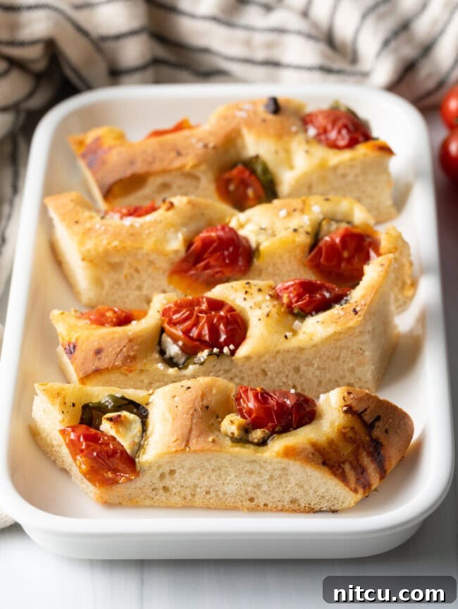 Slices of tomato basil focaccia bread on a white platter.