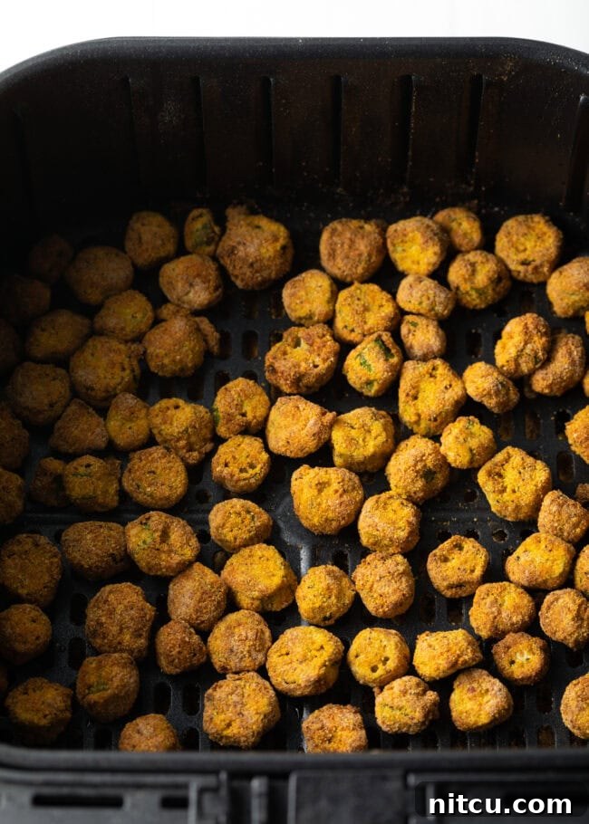 Top down pieces of fried okra in air fryer basket.
