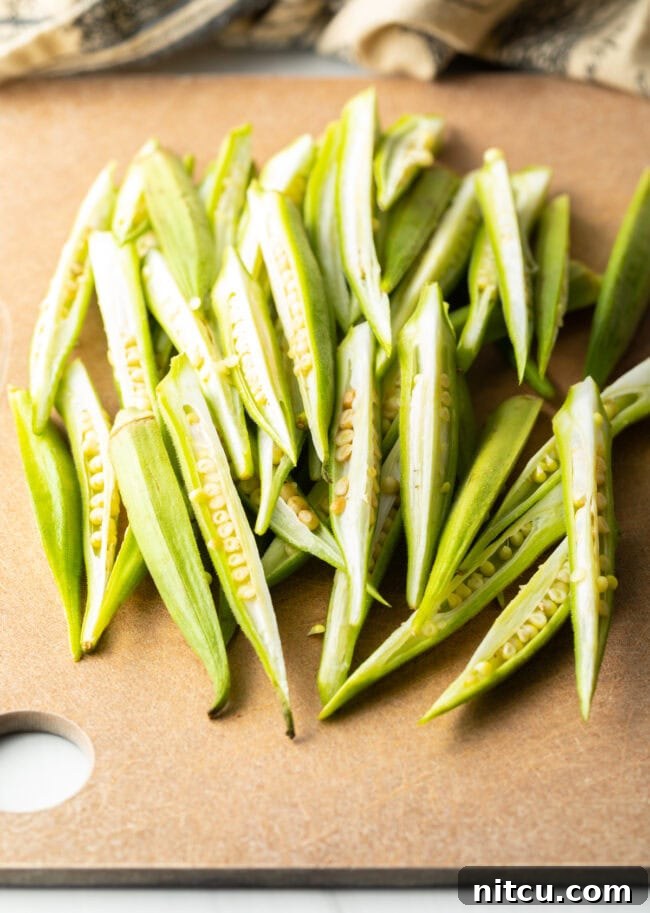 Raw fresh okra sliced into sections on a cutting board.