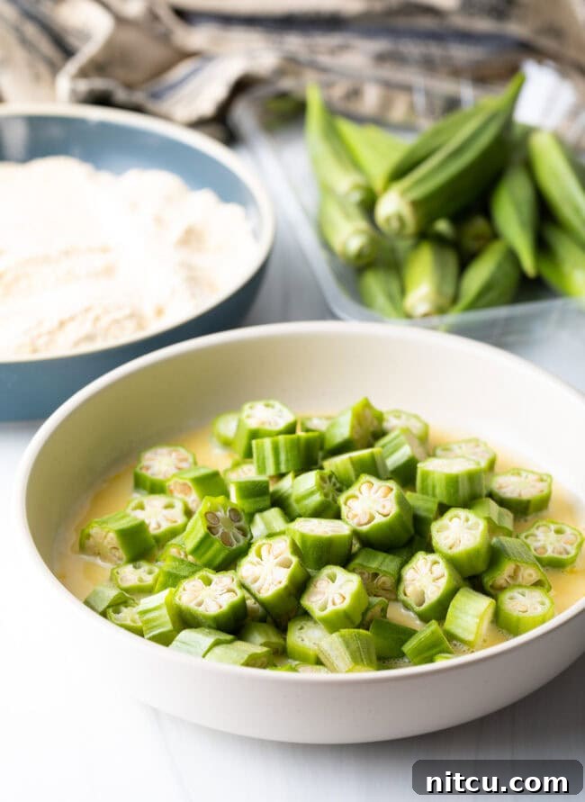 Raw pieces of okra in egg wash bowl.