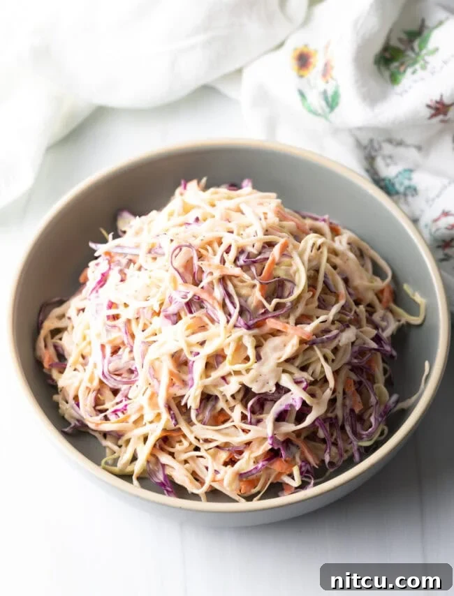 A top-down view of shredded coleslaw generously coated in creamy dressing, served in a rustic bowl.