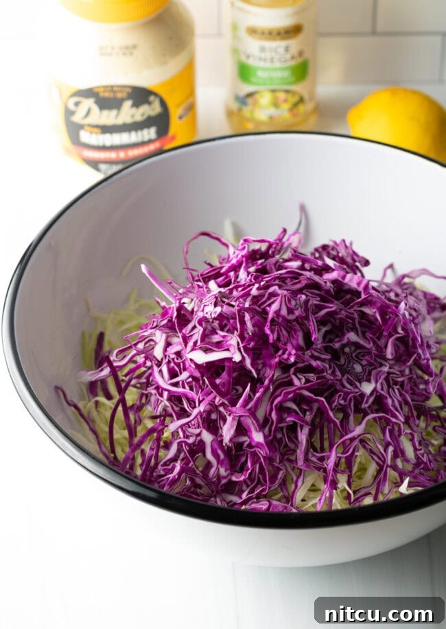 A large mixing bowl filled with vibrant shredded red and green cabbage, ready for the next step.
