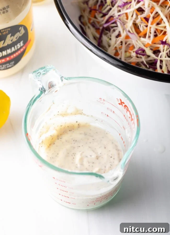 A top-down view of the creamy coleslaw dressing, perfectly mixed and ready to be poured, in a measuring cup.