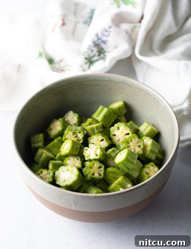 Sliced okra pieces coated in an egg wash, ready for the next breading step.