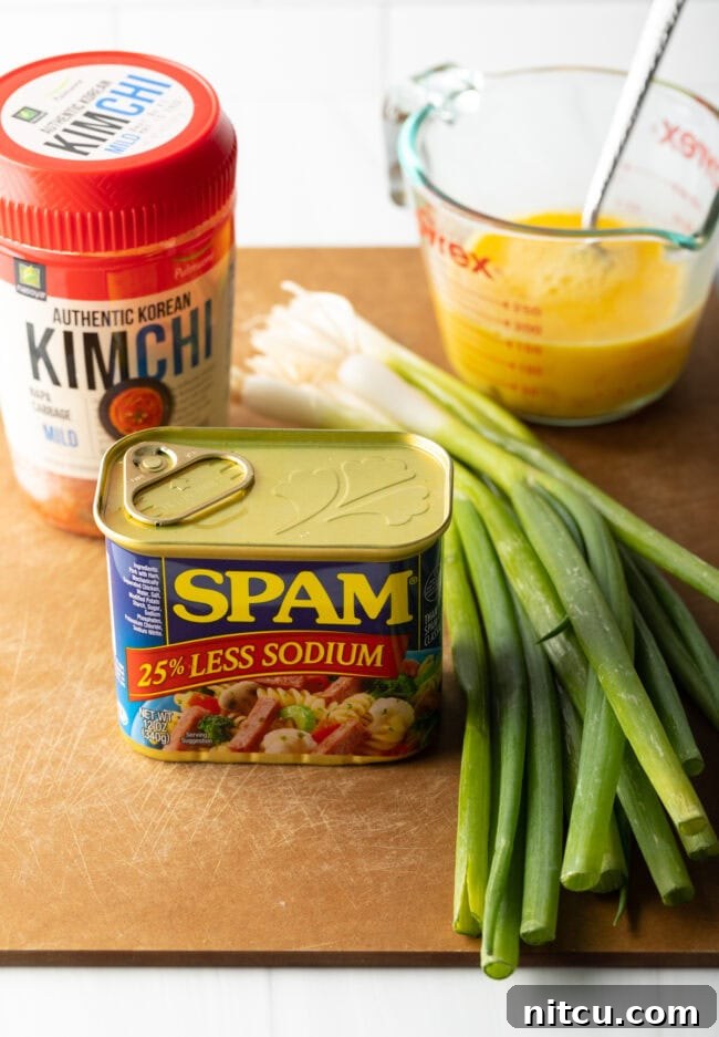 Ingredients on a cutting board: kimchi, can of spam, scrambled raw eggs, fresh green scallions.