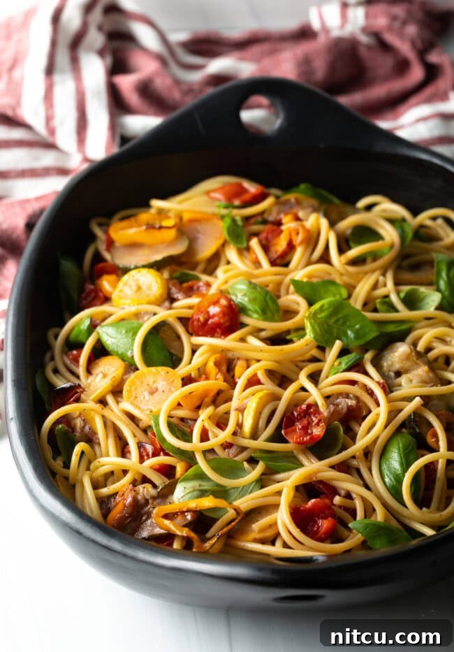 Tossed pasta and vegetables in a large bowl, coated with sauce.