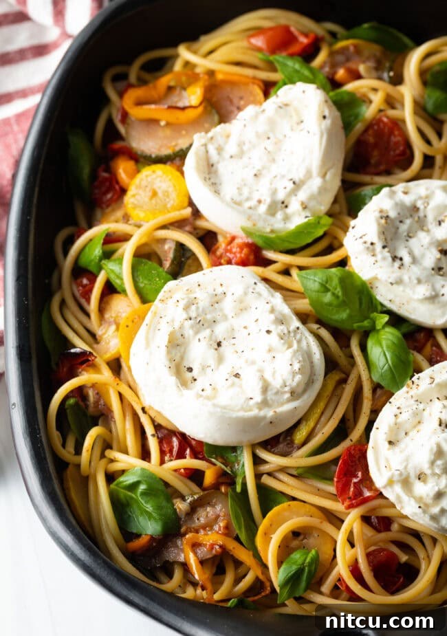 Top down view of a large platter of pasta with burrata and summer roasted vegetables, ready to serve.