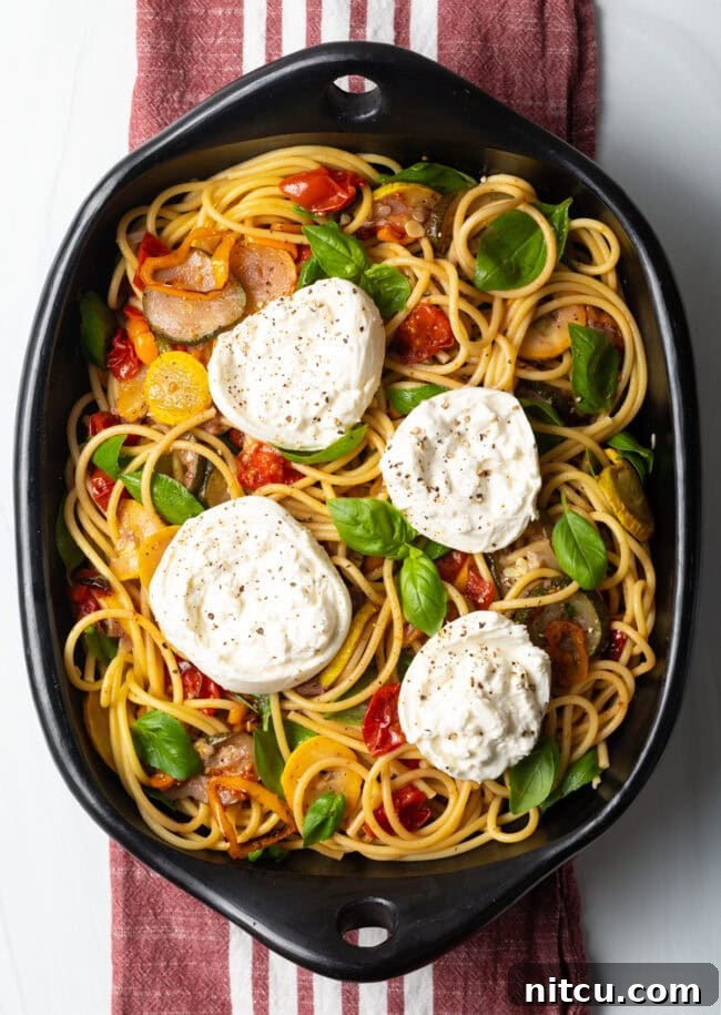 Top down view of pasta burrata with roasted summer vegetables, showcasing the creamy cheese.