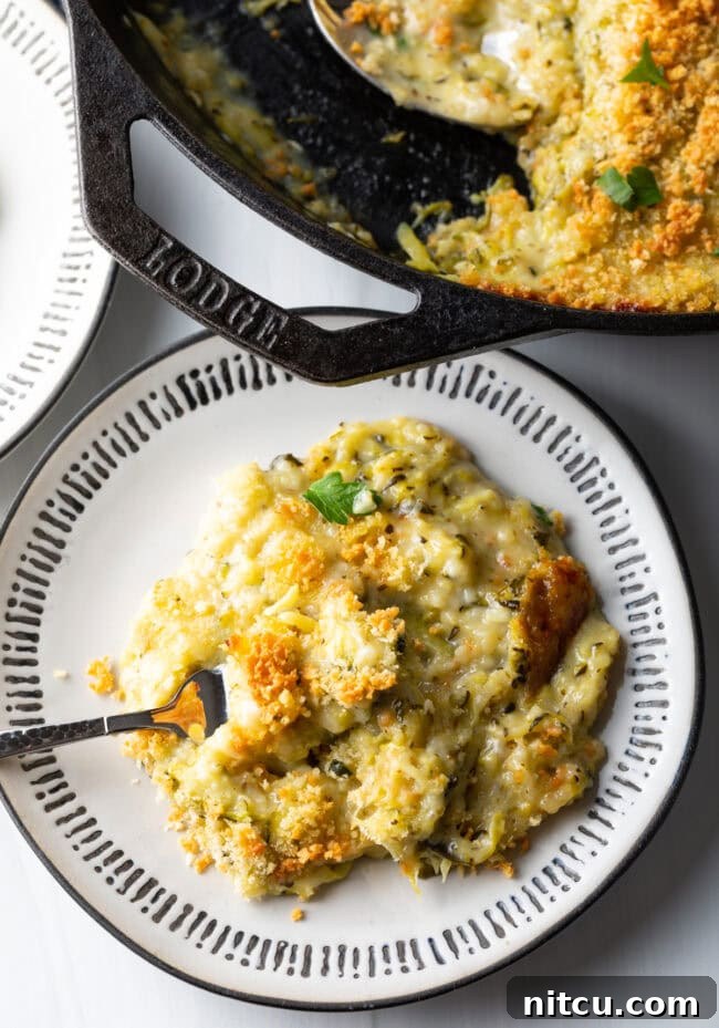 Top down view cheesy zucchini casserole portion on a plate with fork.
