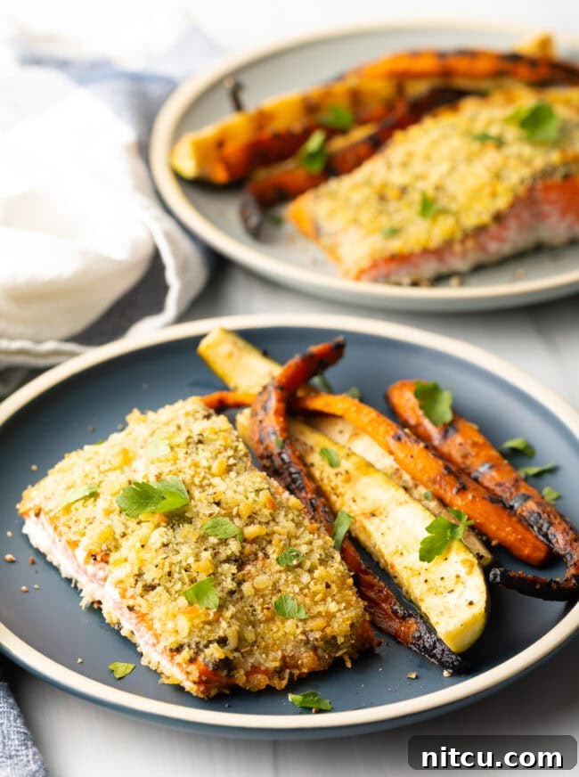 Bake pesto salmon at 400 degrees, serve on a plate with grilled veggies.
