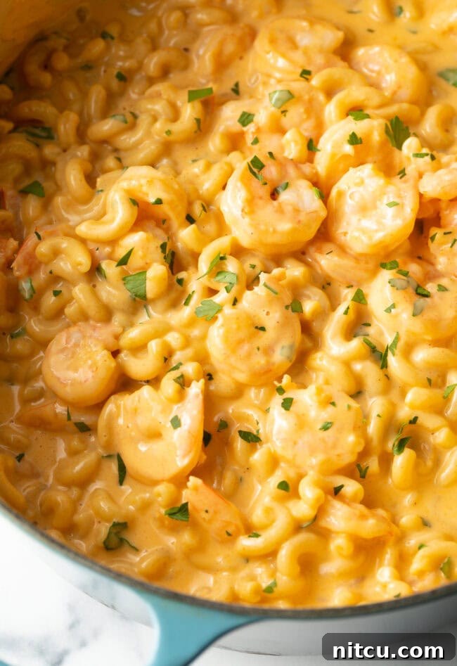 Shrimp Mac and Cheese - Top down view of creamy mac and cheese with shrimp in a pot, ready to be served.