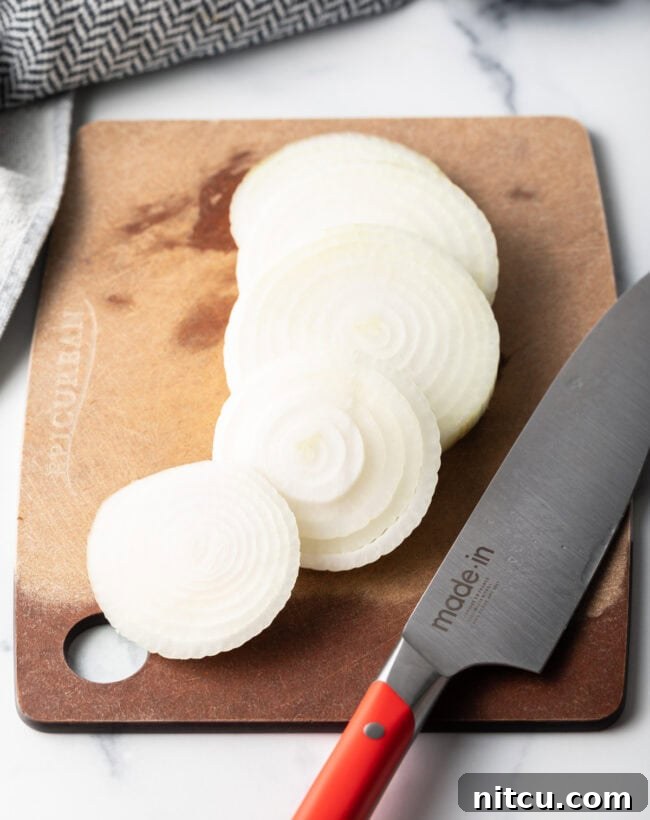 Sliced onions on a cutting board with a knife.