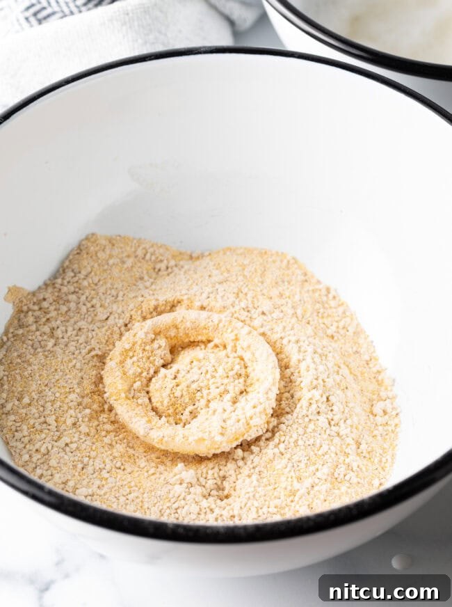 Onion ring in a bowl with breading mixture.