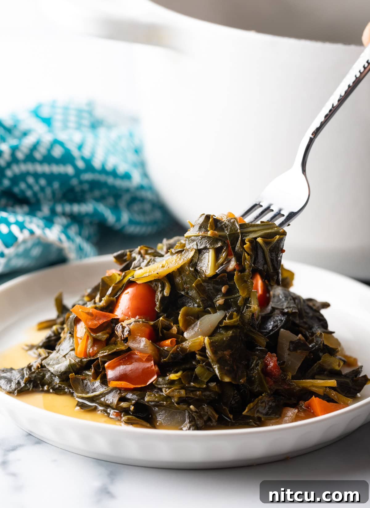 Fork digs into a plate filled with Callaloo greens. A fork digging into a plate piled high with tender Callaloo greens, ready to be enjoyed.