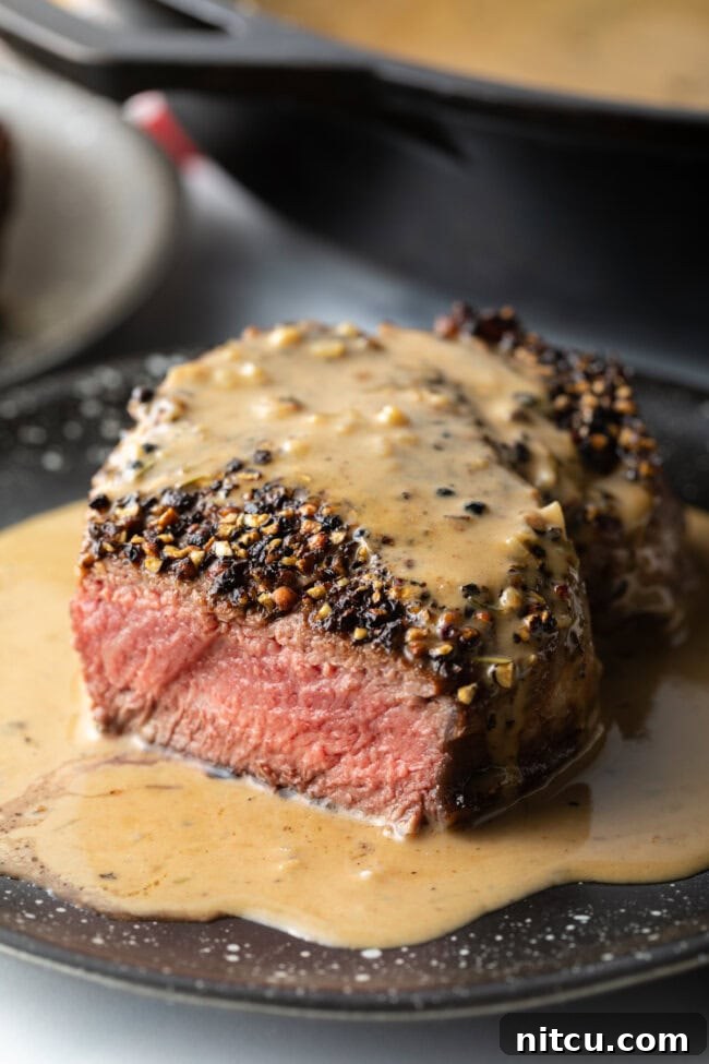 Close view of steak au poivre with bite removed, showing medium rare cook on the inside.