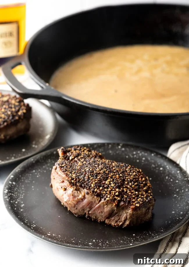 Peppercorn steak seared and resting on a plate.