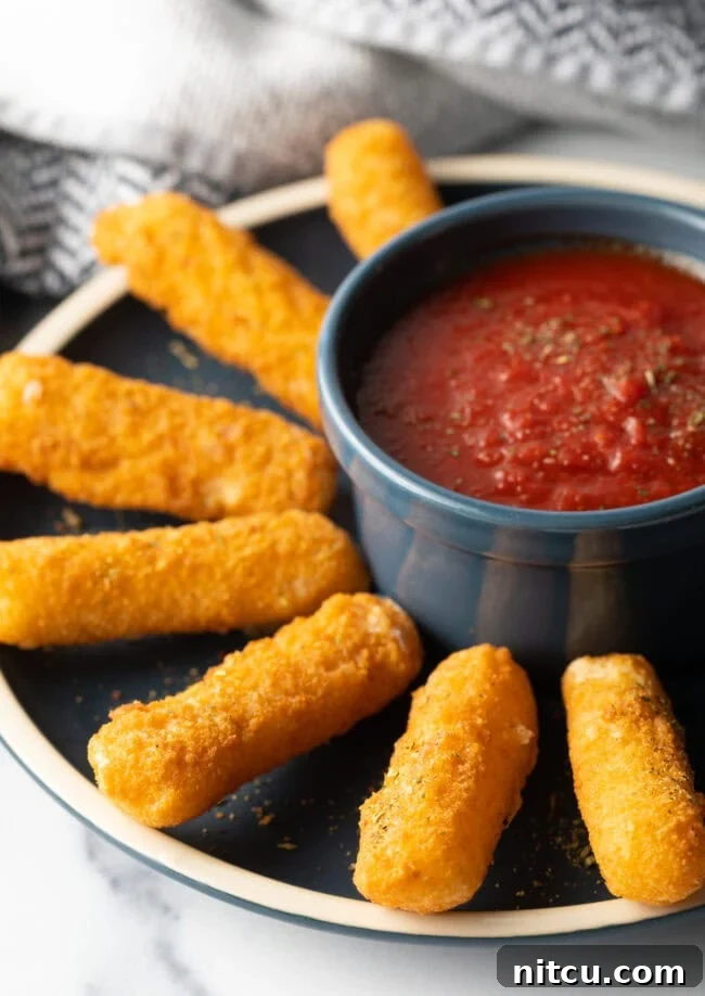 Homemade Air Fryer Mozzarella Sticks - Plate of mozzarella cheese sticks on a plate with marinara sauce in ramekin.