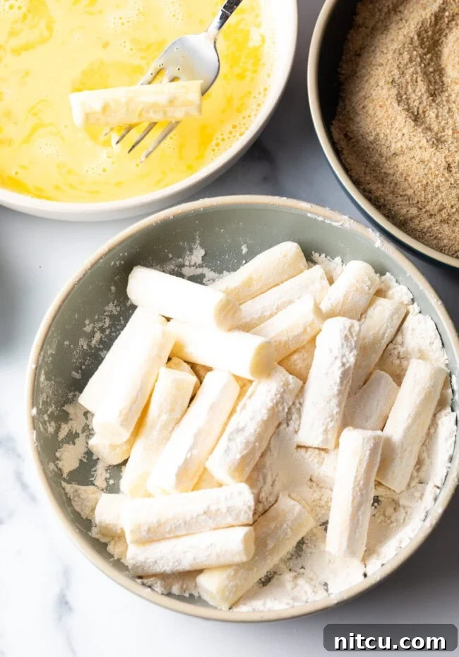 String cheese sticks in a bowl with flour.