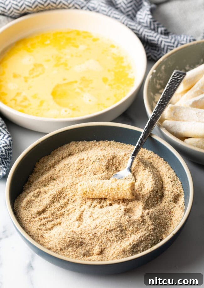 String cheese stick in a bowl with breadcrumbs.