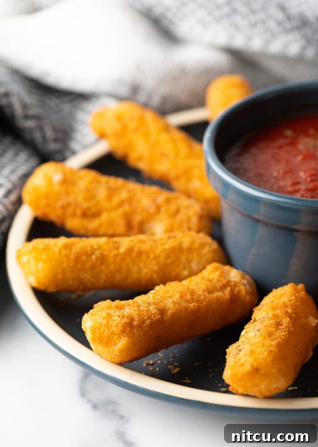 Mozzarella Sticks in Air Fryer - Side view air fried mozzarella sticks on a plate.