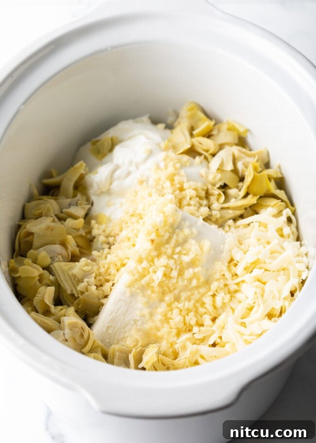 Crock Pot with cream cheese, parmesan cheese, minced garlic, and artichoke hearts.
