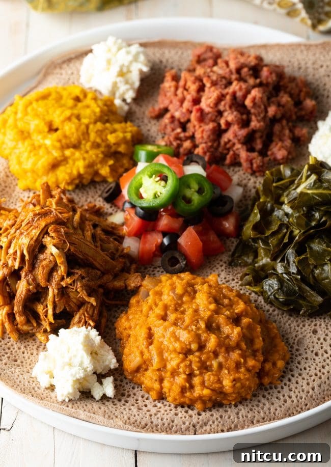 A beautifully arranged Ethiopian shared platter, showcasing various vibrant dishes including lentil stews, greens, and injera bread, reflecting a communal dining experience.