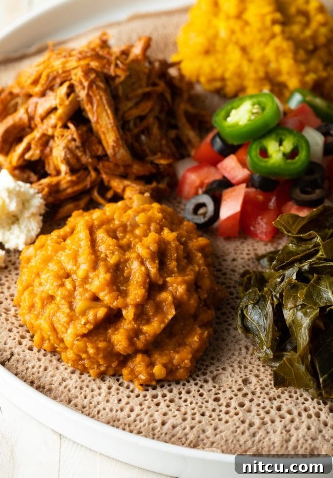 A traditional Ethiopian spread featuring Misir Wot, various stews, and vegetables served atop Injera bread, capturing the essence of a shared meal.