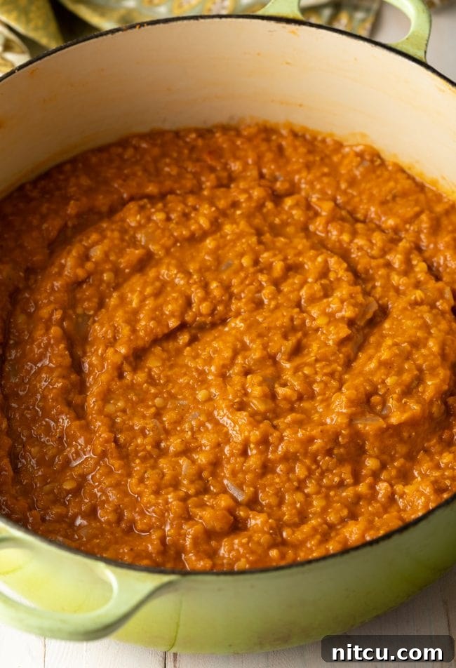 The rich, cooked Ethiopian Red Lentil Stew (Misir Wot) simmering gently in the pot, showcasing its thick, porridge-like consistency and deep red color.