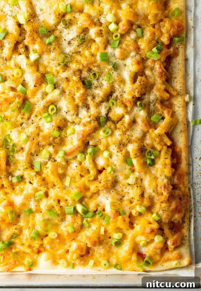 Top down macaroni and cheese pizza with fresh scallions.