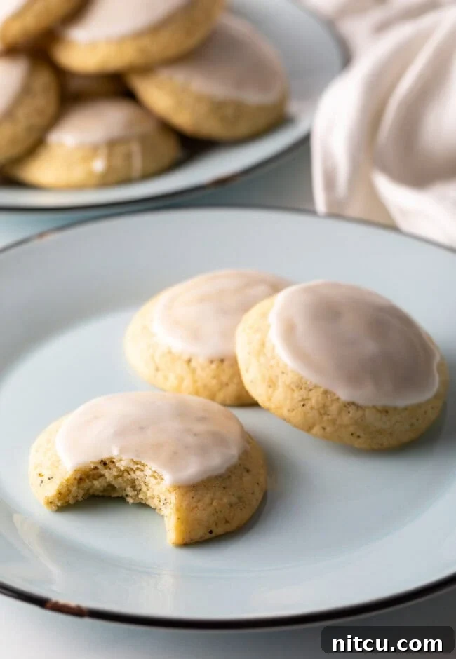 Three perfectly baked Earl Grey cookies, or tea cakes, on a plate, one with a bite taken out.