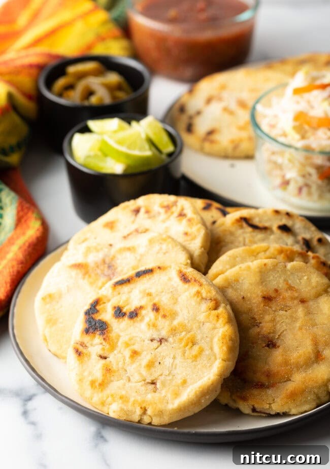 Thick corn pupusas recipe on a plate, garnished with curtido.