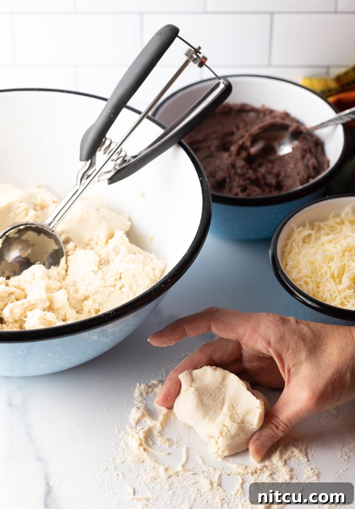 Hand pinching the edges of the dough together to form a sealed ball.