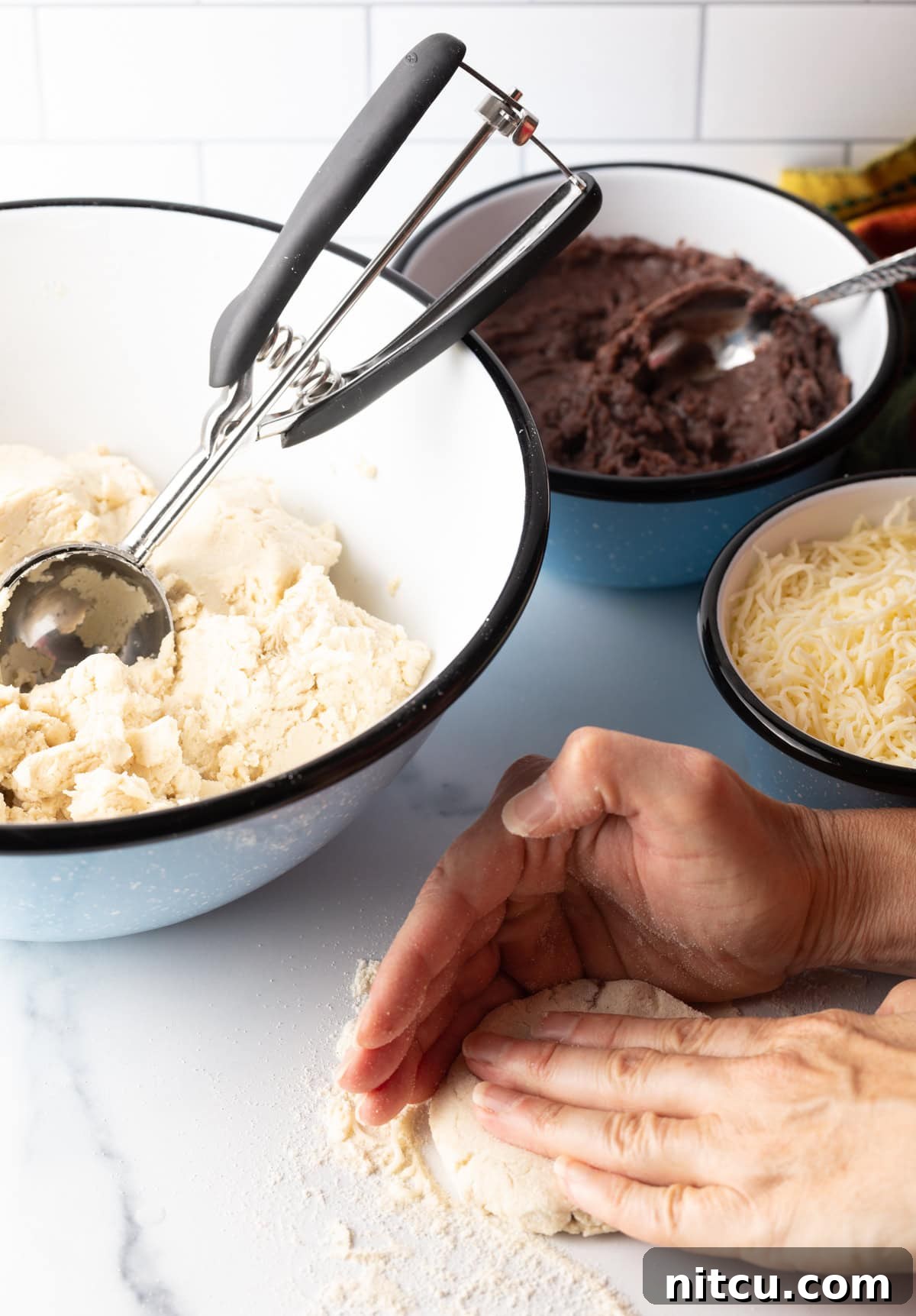 Hand flattening a sealed dough ball into a thick disc.