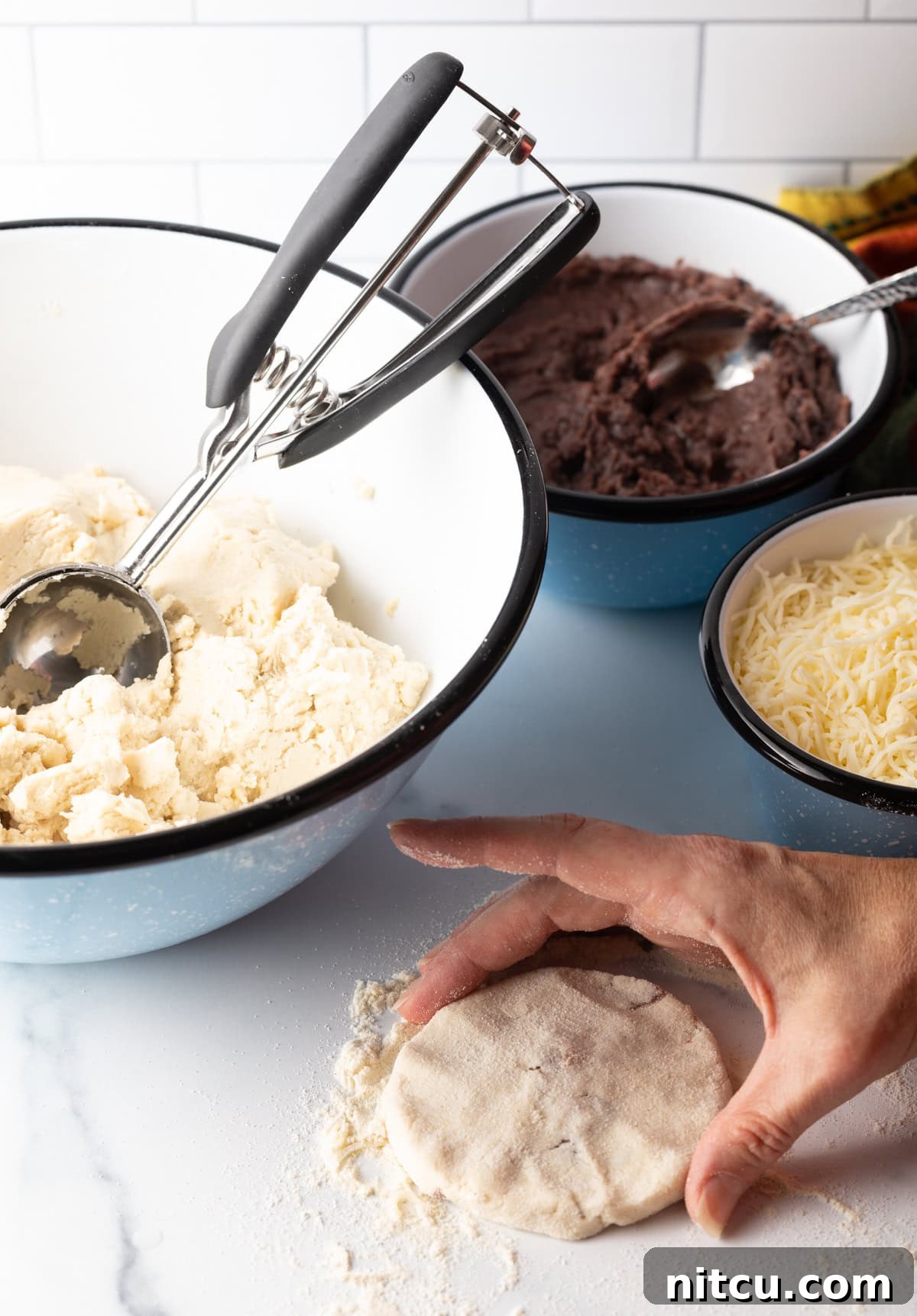 Hand showing a perfectly flattened, filled pupusa disc.