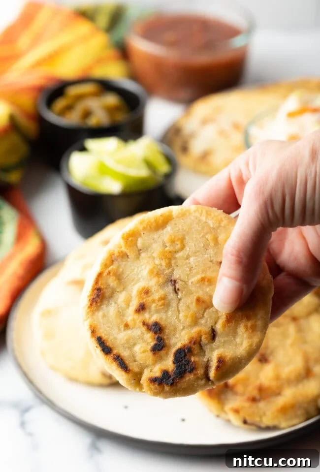 How to Make Pupusas - Hand holding a freshly cooked pupusa, showcasing its golden crust.