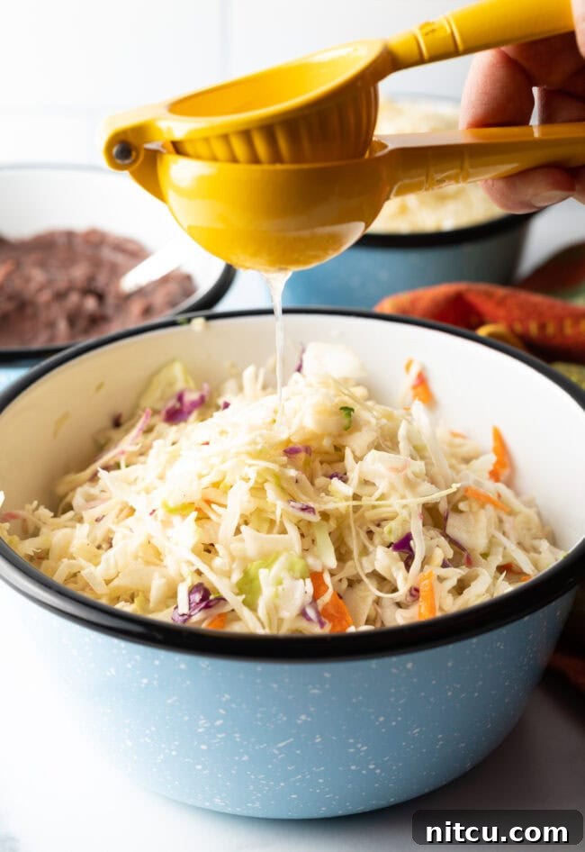 Squeezing a lime into a bowl of shredded cabbage and carrots for curtido.