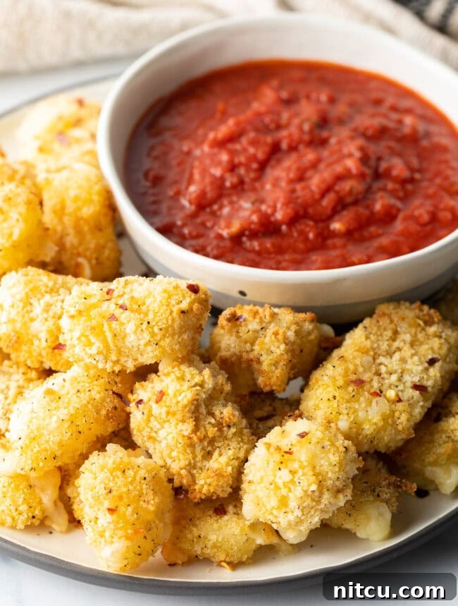 Close view cheese curds recipe on a plate with ramekin of marinara sauce.