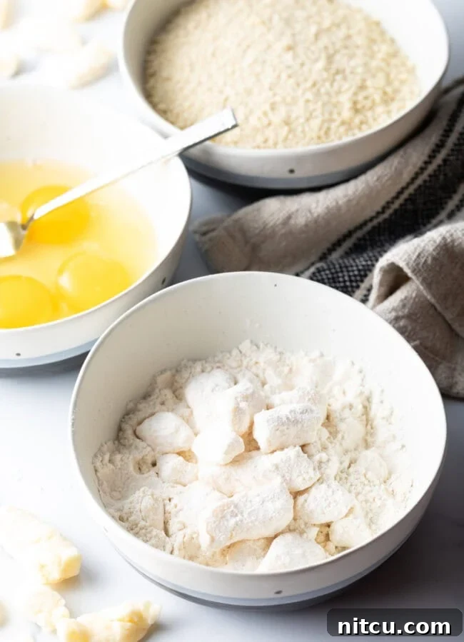 Chunks of cheese coated in flour in a white bowl.