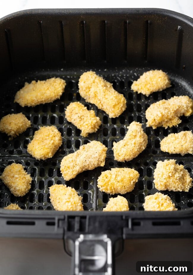 Uncooked breaded cheese curds in an air fryer.