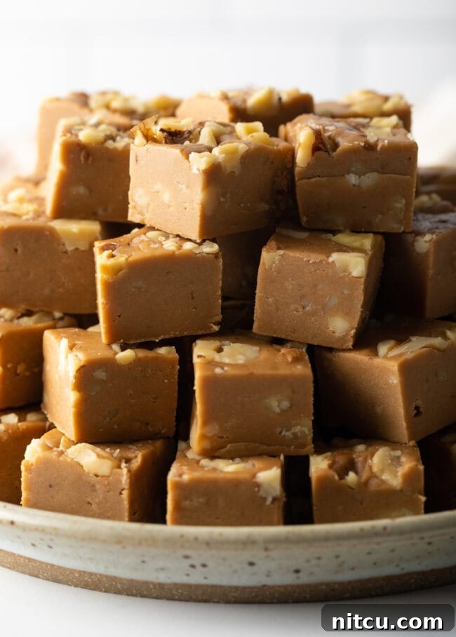 Neatly stacked pieces of maple fudge on a plate, showcasing their smooth texture and inviting golden-brown color.