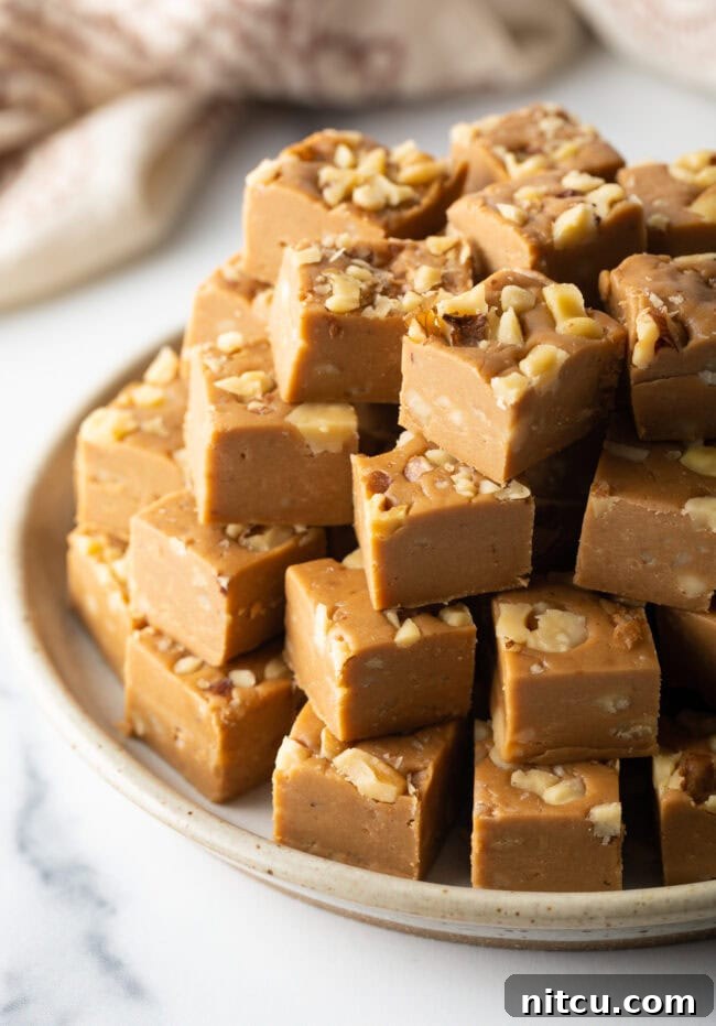 A stunning plate of maple fudge squares adorned with walnuts, artfully stacked like a pyramid, ready to be devoured.