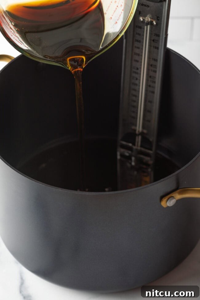 Close-up shot of rich, amber maple syrup being poured into a large saucepot, ready for cooking.