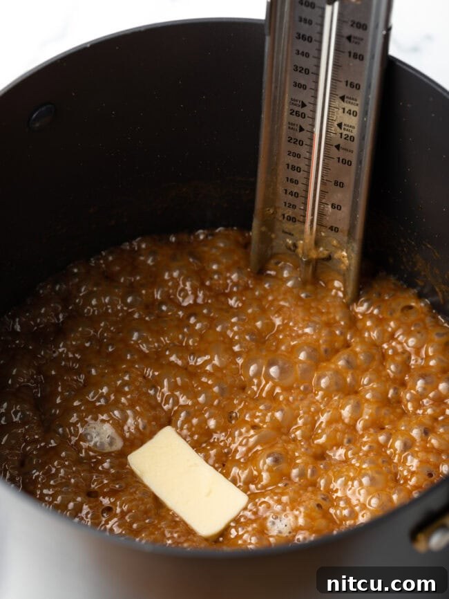Melted butter has just been added to the hot maple syrup and cream mixture in the saucepot, glistening on the surface.