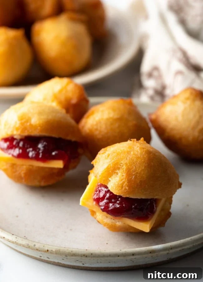 An array of mini fried dough bites, some filled with cheese and jam, others with minced meat.