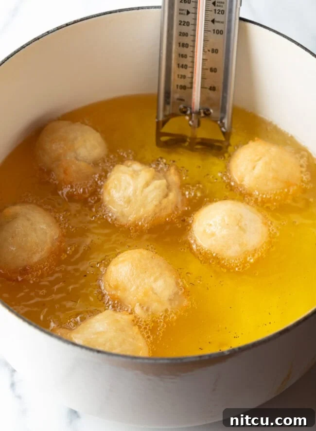 Dough balls gently frying in hot oil, beginning to turn golden.