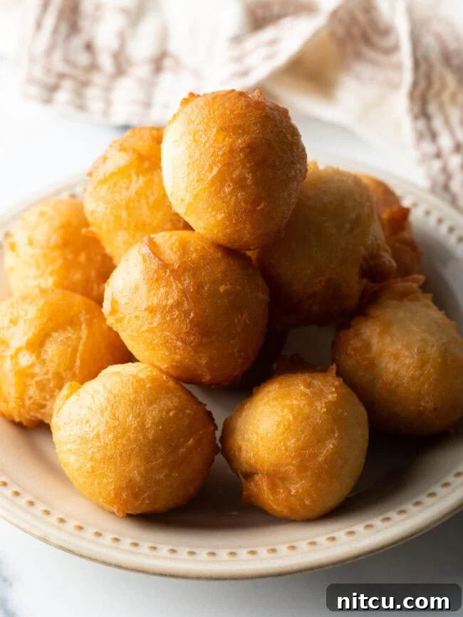 A plate piled high with beautifully fried, golden-brown fat cakes, ready to be filled.